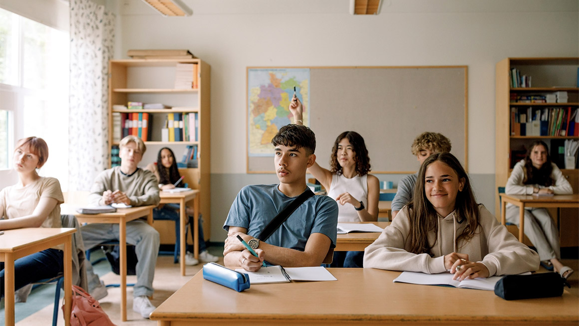 Girls and boys learning while sitting at desk in classroom 