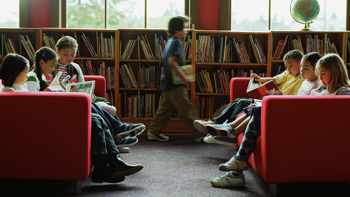 Group of children sitting in library, reading books