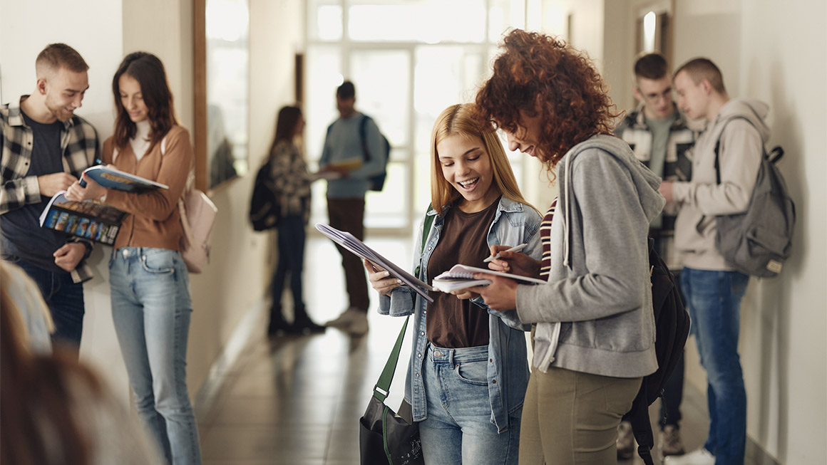 Student talking to her friend in a school hallway. 
