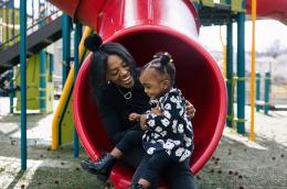 Dana Mitchell and her daughter play on the slide at a park